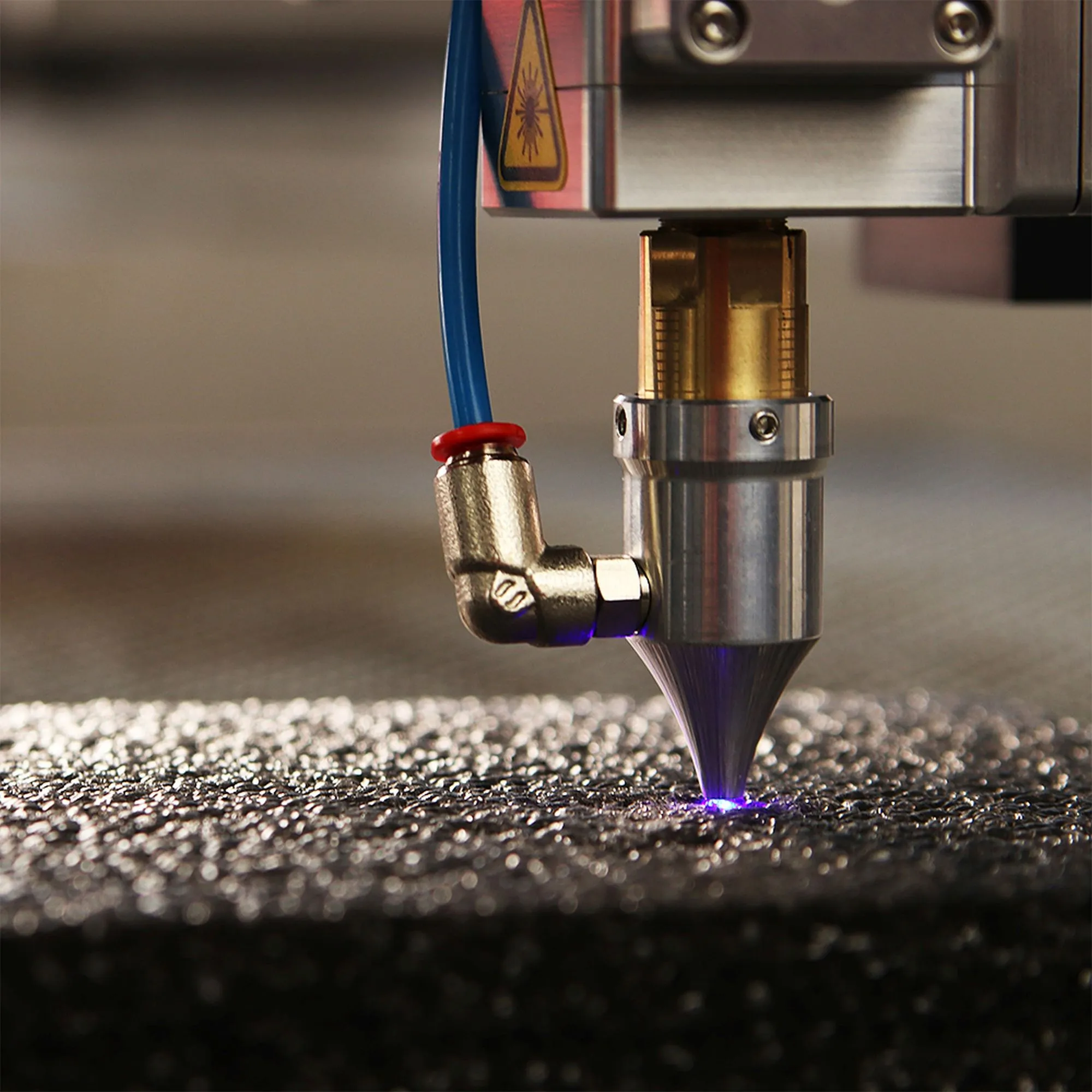 Laser marking head with air assist cutting a fine violet beam into a metal surface