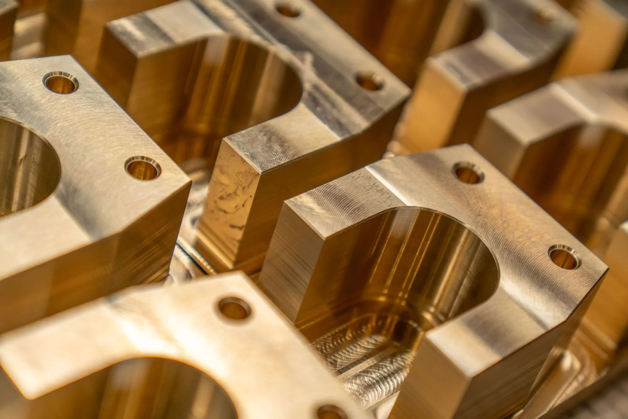 Precision-machined metal components with milled pockets and bored holes, resting under shop lighting